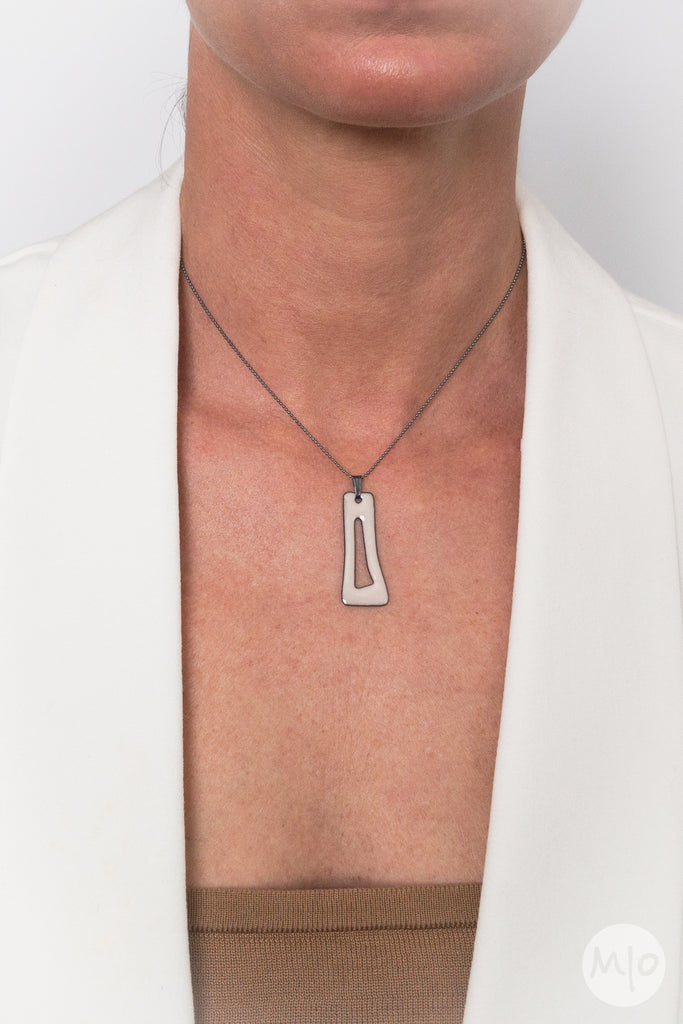 This artfully inspired pendant creates a subtle texture on skin defined by a minimalist shape. The perfectly considered sterling silver bead chain is oxidized (blackened) to create a thin line and delicate drape around the neck. 