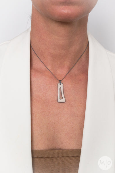 This artfully inspired pendant creates a subtle texture on skin defined by a minimalist shape. The perfectly considered sterling silver bead chain is oxidized (blackened) to create a thin line and delicate drape around the neck.