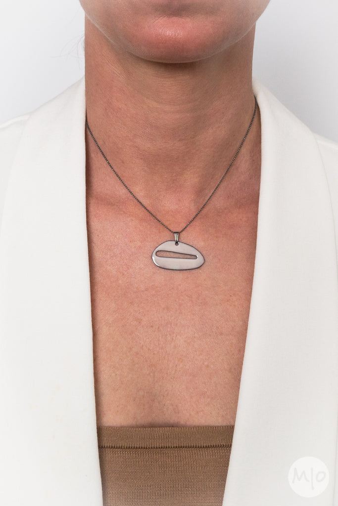 The Nudes Collection PRONE Pendant is an artfully inspired pendant creates a subtle texture on skin defined by a minimalist shape. The perfectly considered sterling silver bead chain is oxidized (blackened) to create a thin line and delicate drape around the neck.